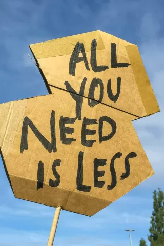 Schild mit Beschriftung "All you need is less"